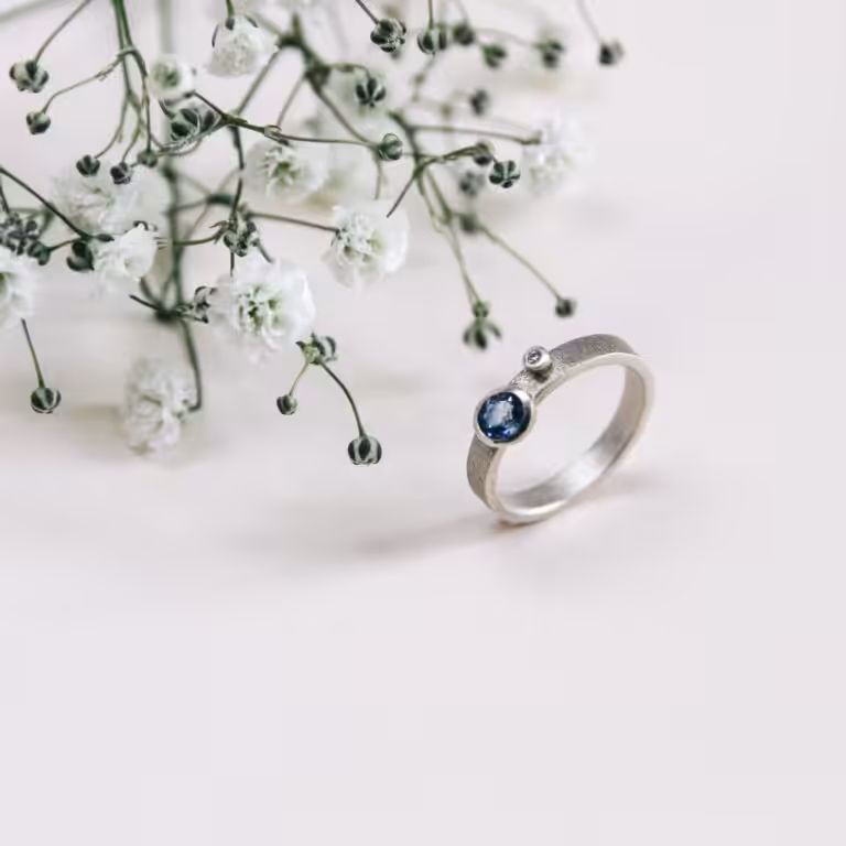 A Clifton Rocks wedding ring with a sapphire blue stone standing up on its own