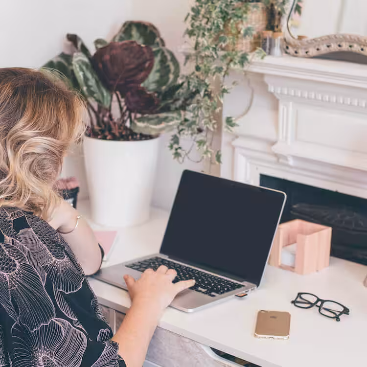 A photo of Studio Cotton founder Aime working at her desk on her Macbook laptop