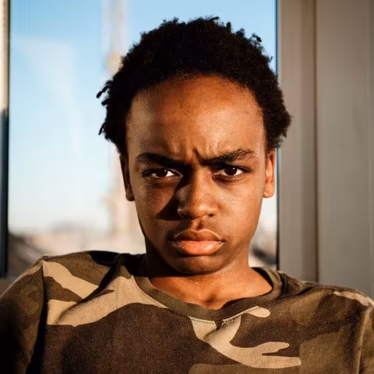 A portrait of a young man looking disgruntled at the camera