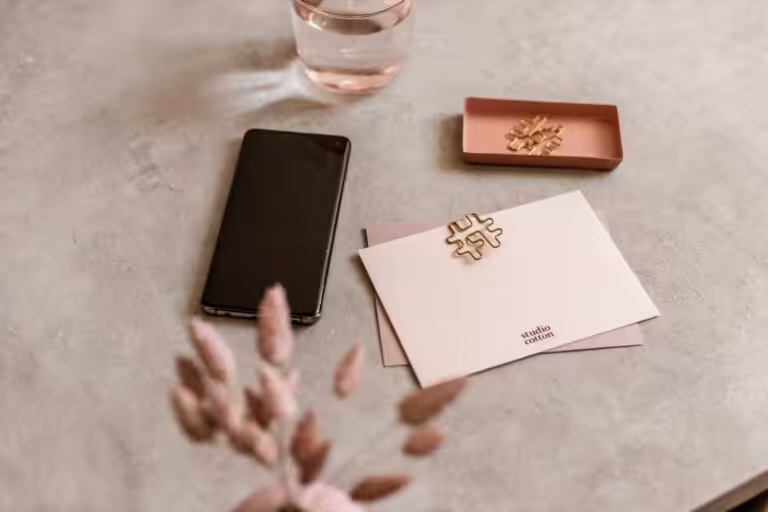 A workspace scene at the Studio Cotton design studio including notecards, paperclips and an iPhone