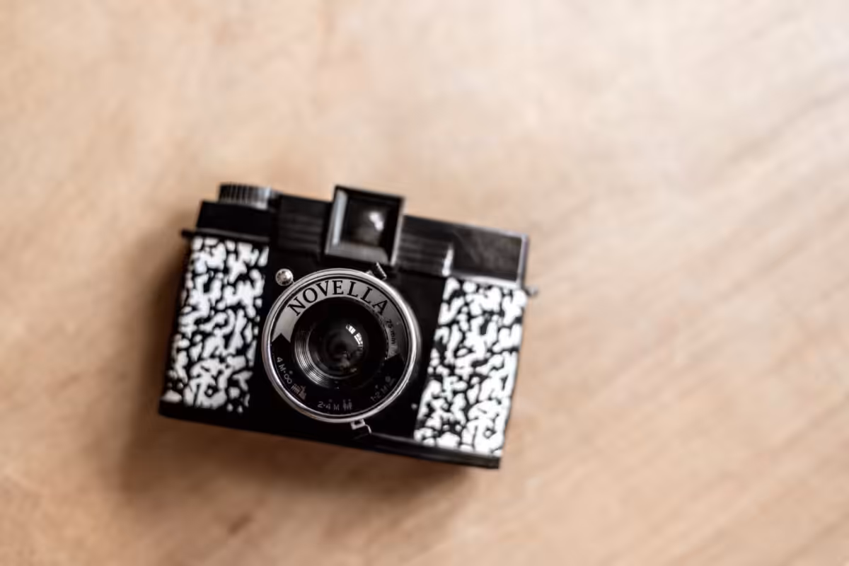 A black and white Novella camera resting on a wooden table