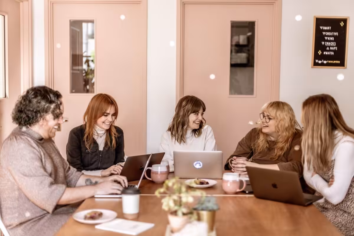 The Studio Cotton team sitting around a desk smiling.
