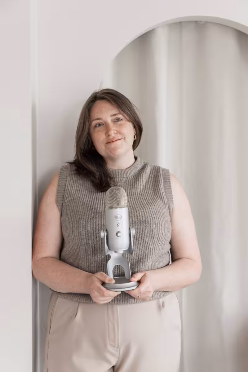 Aime, who builds great podcast websites, holding a podcasting microphone. 