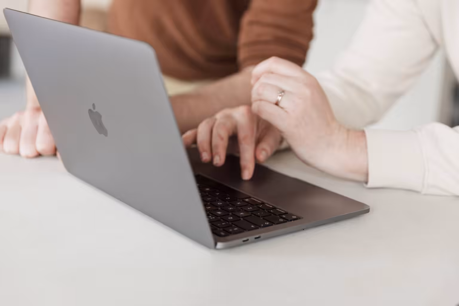 A close up of two Studio Cotton team members working on an Apple MacBook laptop.