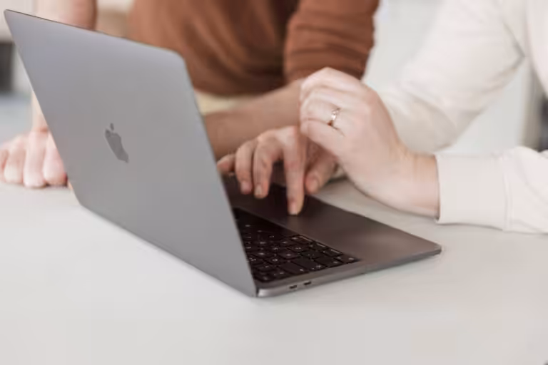 A close up of two Studio Cotton team members working on an Apple MacBook laptop.