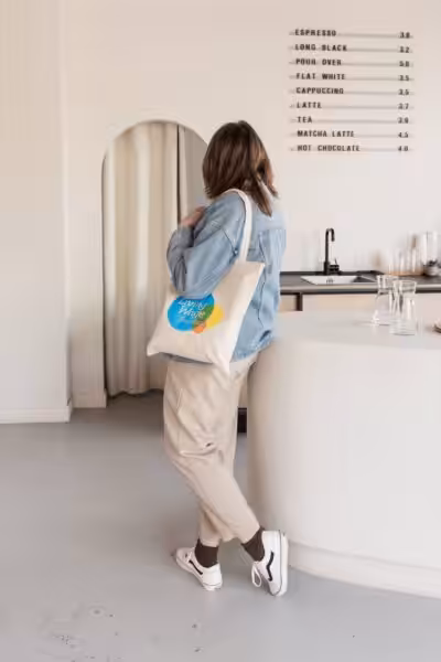 Studio Cotton's Aime turning and facing away fom the camera with a National Living Wage tote bag.