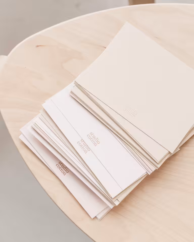 A pile of blank Studio Cotton notecards on a wooden table.