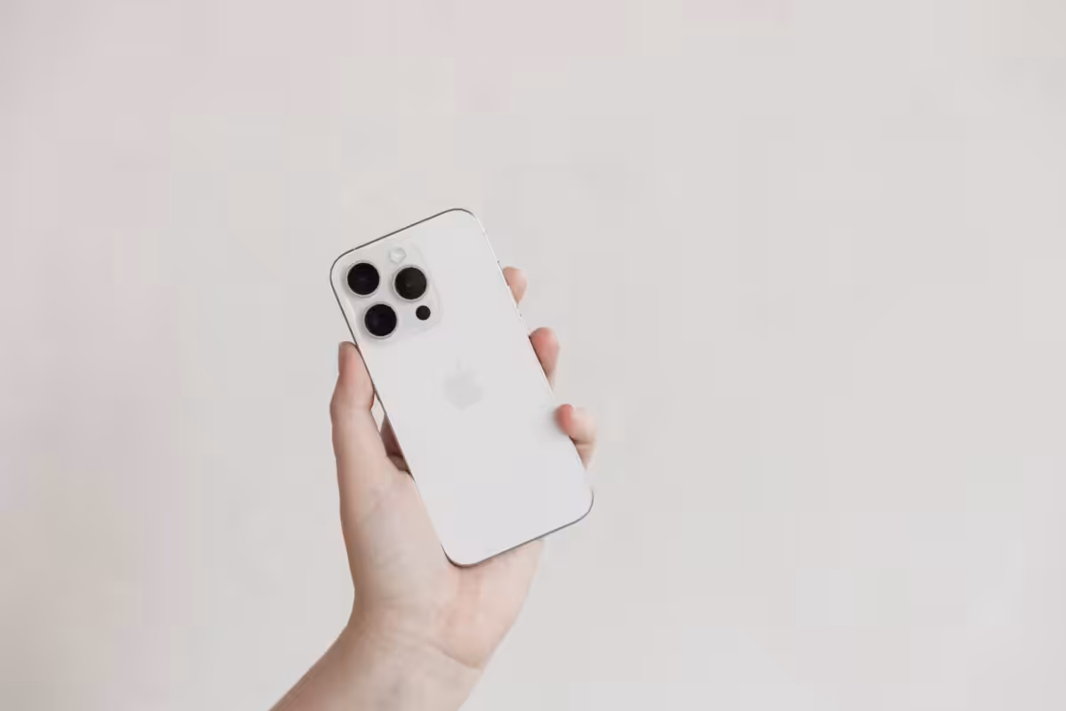 A white Apple iPhone being held up in a hand.