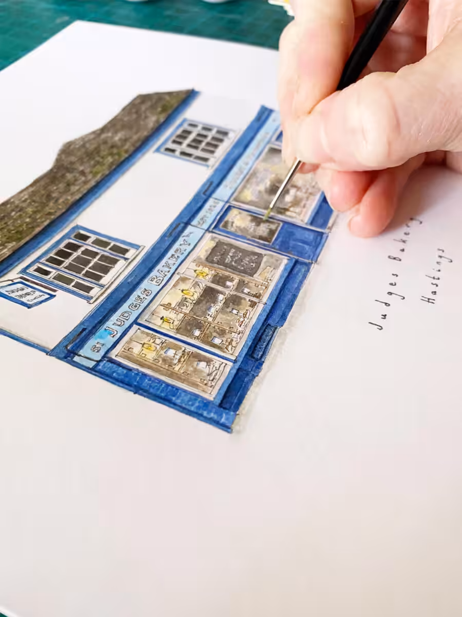 A hand painting the watercolour illustration of Judges Bakery