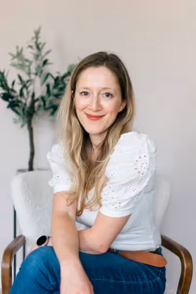 Emma wears a white blouse and smiles at the camera