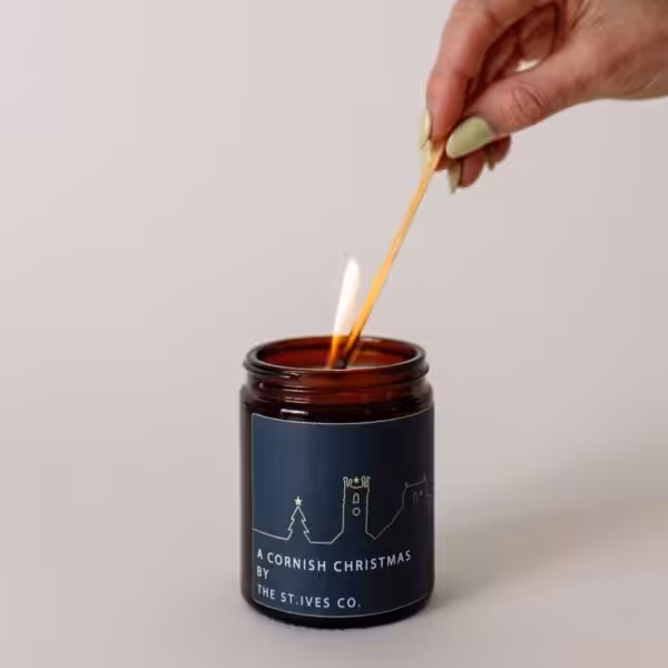 Hand lighting an artisan candle with a long match and pale green nails