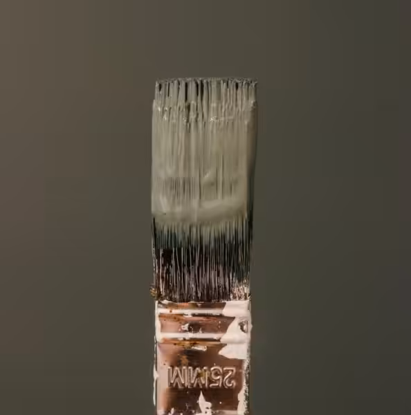 Paintbrush with green paint on it matching the green background